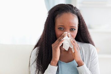 Close up of woman on sofa blowing her nose