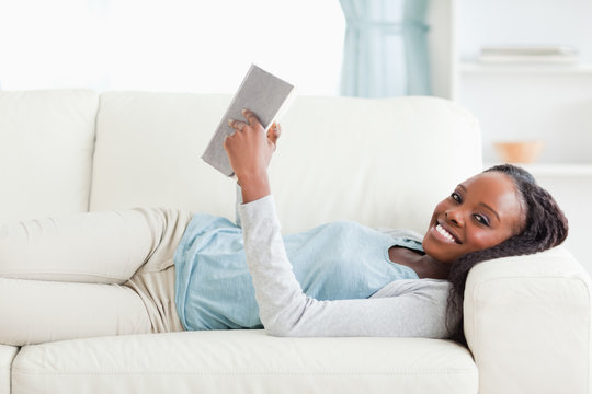 Woman lying on couch reading a novel