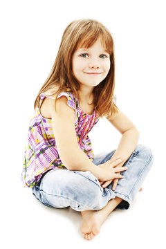 A pretty little girl sitting on the floor in jeans