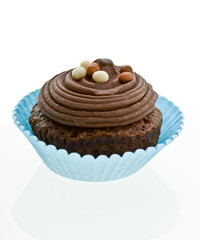 Swirly chocolate cupcake with decorations on white.