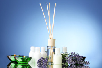 Obraz na płótnie Canvas Bottle of air freshener, lavander and candles on blue background