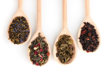 Different dry green and black tea in wooden spoons