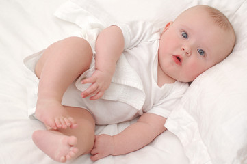 Baby boy lying on white sheets