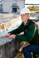 Mature man manual worker in white near sewage treatment basin
