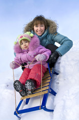 Mother and little daughter sliding in the snow
