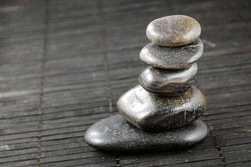 black zen stones on bamboo place mat, concept of balance