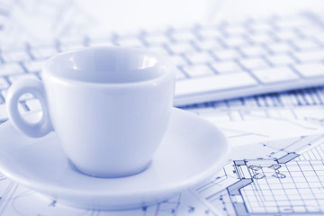 keyboard, white cup and architectural drawings of the modern hou