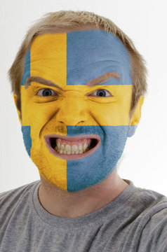 Face of crazy angry man painted in colors of Sweden flag