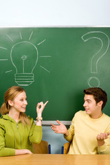 Two students with light bulb and question mark on chalkboard