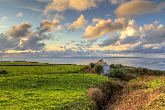 Irish cottage house near the ocean at sunset