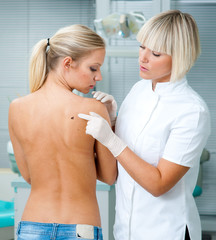 doctor inspecting woman patient skin
