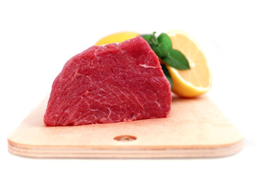 Beef steak  on meat hardboard with green leaf and lemon.