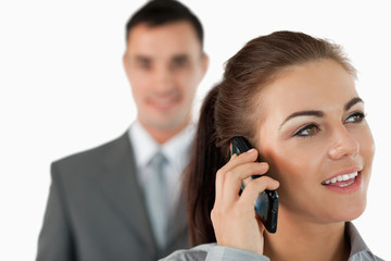 Close up of young businesswoman on the phone with colleague behi