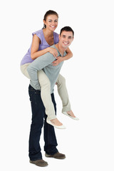 Fototapeta premium Young male carrying his girlfriend piggyback