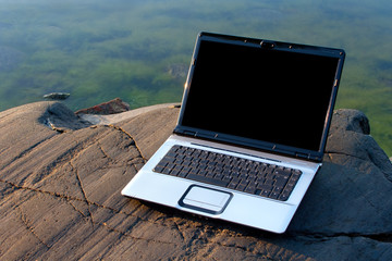 Laptop on the beach rock in morning
