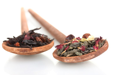 Green and black dry tea leaves in woooden spoons