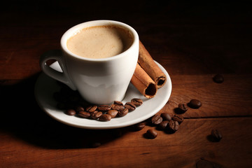 cup with coffee, cinnamon and coffee beans on  wooden table