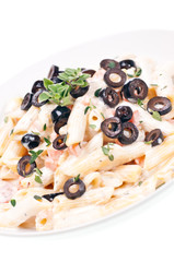 Penne pasta with  cream vegetable sauce and olives close up