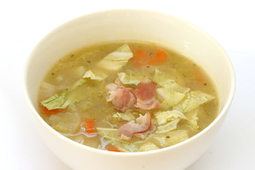 Vegetable cabbage soup in white bowl with bacon pieces