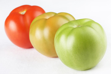 Three tomatoes of different maturity