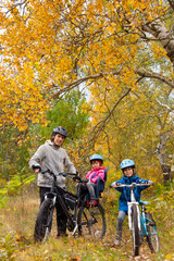 Family cycling outdoors, golden autumn in park, vertical photo