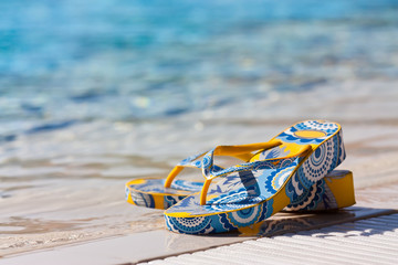 Obraz premium Bright flip-flops by a swimming pool