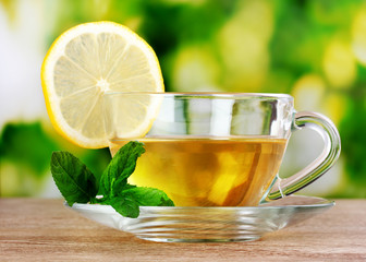 tea with lemon on green leaves background