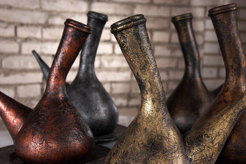 metallic jugs in front of brick wall