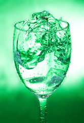 glass with splash on green background