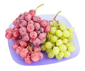 Red and white grapes bunches on blue plate isolated on white