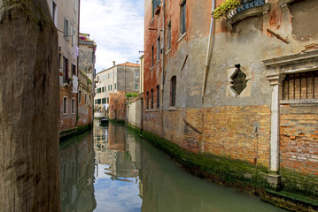 Fototapeta na wymiar Venetian Canal with small boat to the front door, Venice..