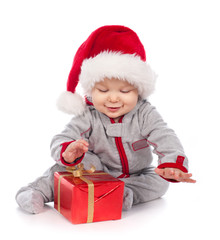Baby in Santa hat playing with Christmas gift box isolated