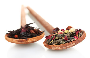 Green and black dry tea leaves in woooden spoons isolated