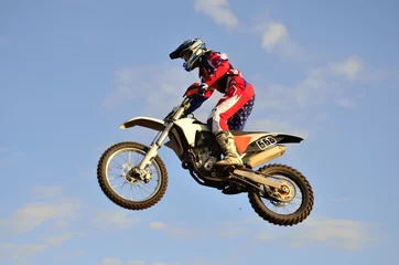 Fotobehang motocross rider on a motorcycle flying through the air © VVKSAM