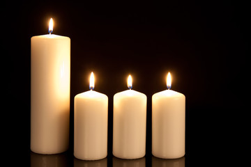 Four white candles on black