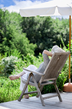 grauhaarige Frau entspannt im Garten