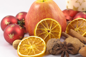 Apfel, Nüsse, Orangen, Kerze und Glaskugeln