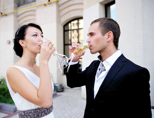 Bride and groom drinking champagne outdoors
