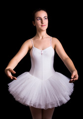 Fototapeta premium Teen girl ballet dancer standing in a tutu on a black background