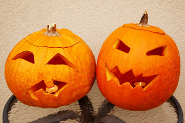 Two pumpkins of Halloween lie on glass little table