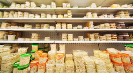 Different salads in plastic containers on shelves in big store
