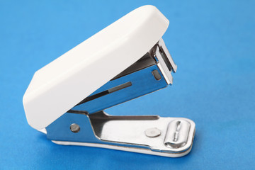 white plastic stapler for work of secretary on blue background