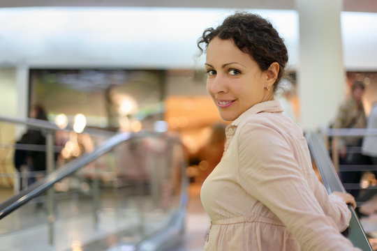 Beautiful young smiling woman standing on escalator at supermark