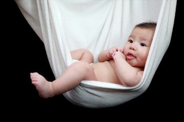 Naked Baby sleeping in White Hammock Sling, isolated on a black background.