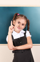 beautiful little girl standing near blackboard in the classroom