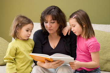 Mother reading a book with her daughters