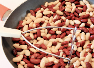 Kidney beans in skillet with masher