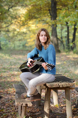 Young girl with guitar in forest, selective focus