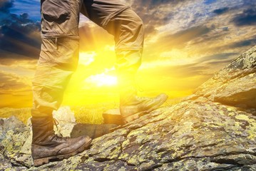 man ascenting by a stones on a sunset background