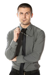 Pensive young  businessman holds a pair of glasses